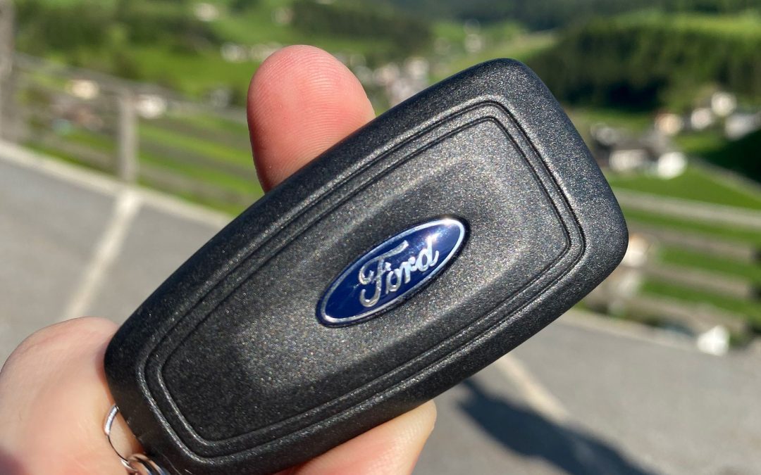 Hand holding a black Ford key fob with the blue Ford oval logo